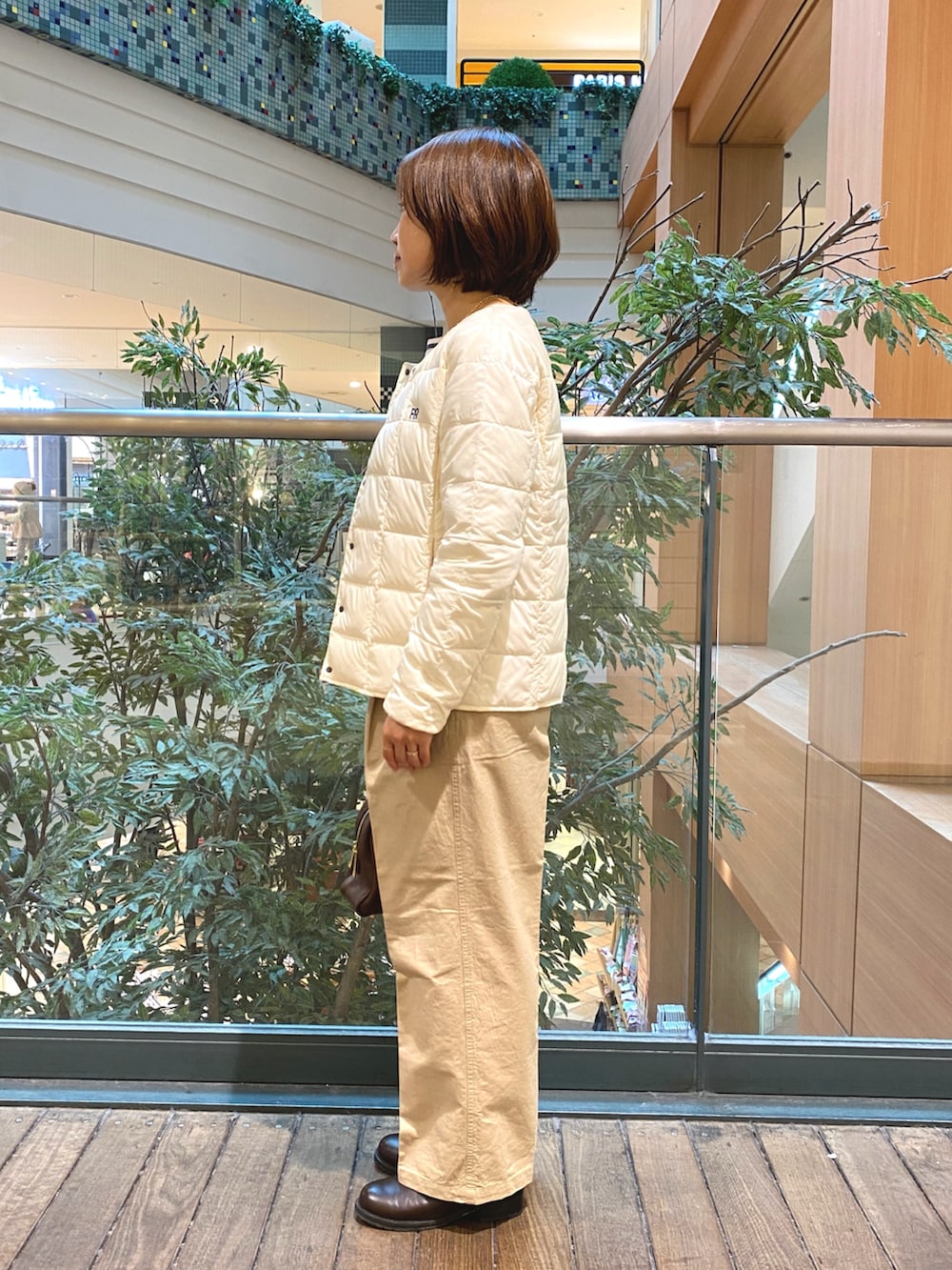 ホワイト系のダウンジャケット/コート、ホワイト系のTシャツ/カットソー、ブラウン系のボストンバッグを着用したレディースの秋コーディネートの3枚目の写真