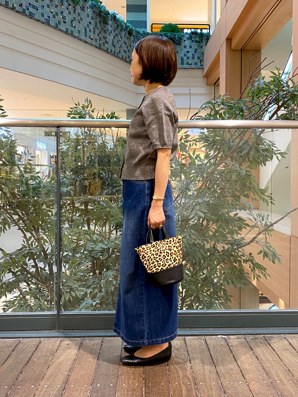 グレー系のニット/セーター、ブルー系のデニムスカート、ベージュ系のショルダーバッグを着用したレディースの秋コーディネートの3枚目の写真