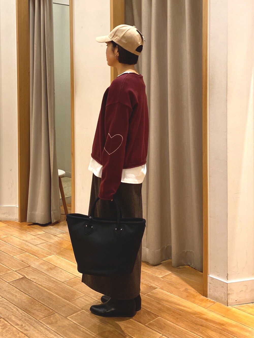 レッド系のニット/セーター、ブラウン系のスカート、ホワイト系のTシャツ/カットソーを着用したレディースの秋コーディネートの4枚目の写真