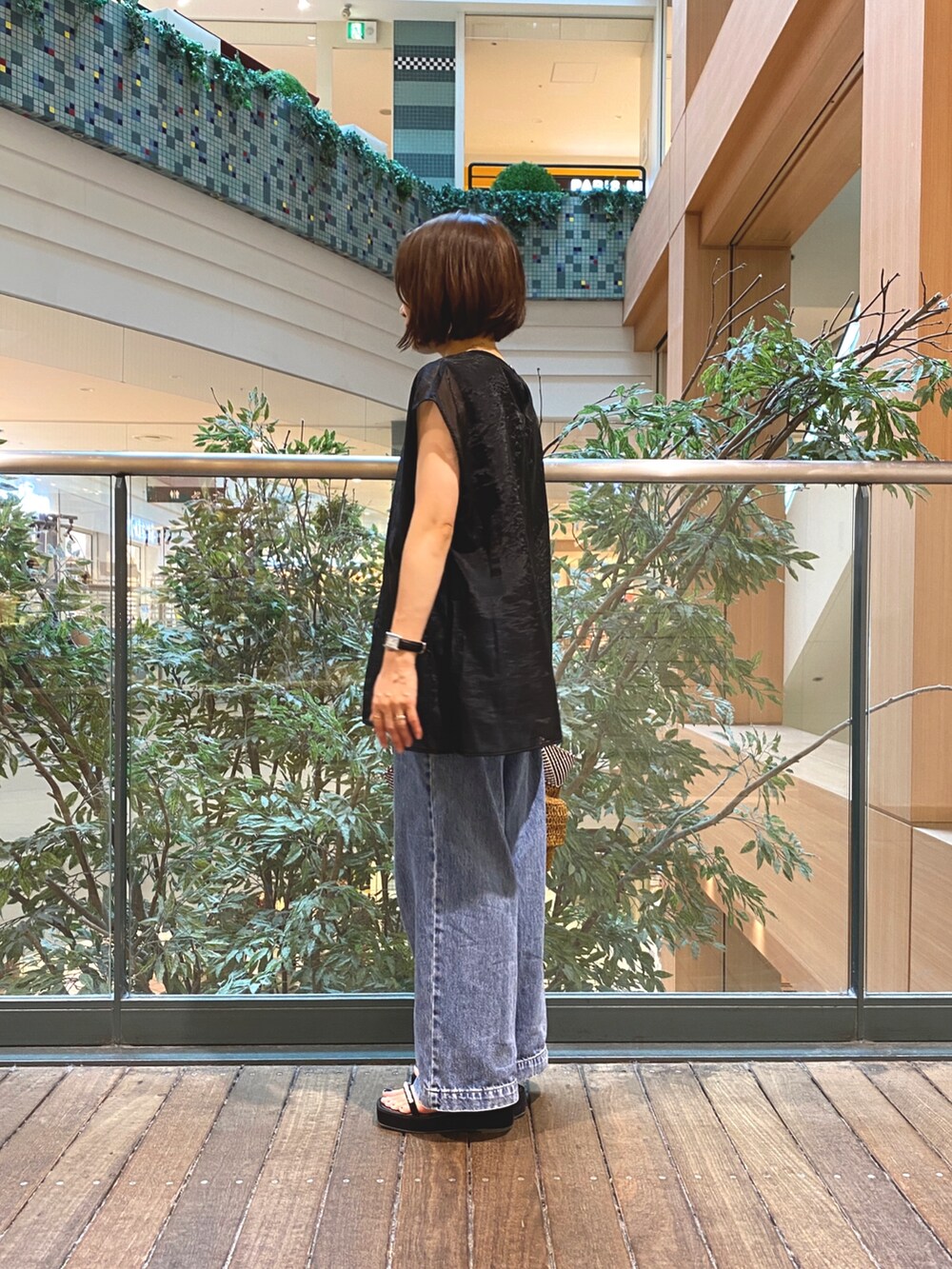 ブラック系のシャツ/ブラウス、ブラウン系のかごバッグ、ブルー系のデニムパンツを着用したレディースの夏コーディネートの6枚目の写真