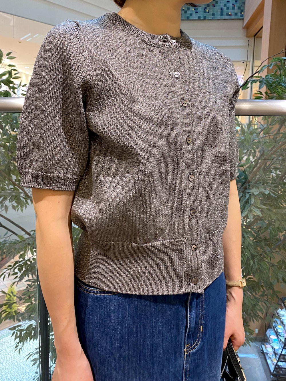 グレー系のニット/セーター、ブルー系のデニムスカート、ベージュ系のショルダーバッグを着用したレディースの秋コーディネートの4枚目の写真