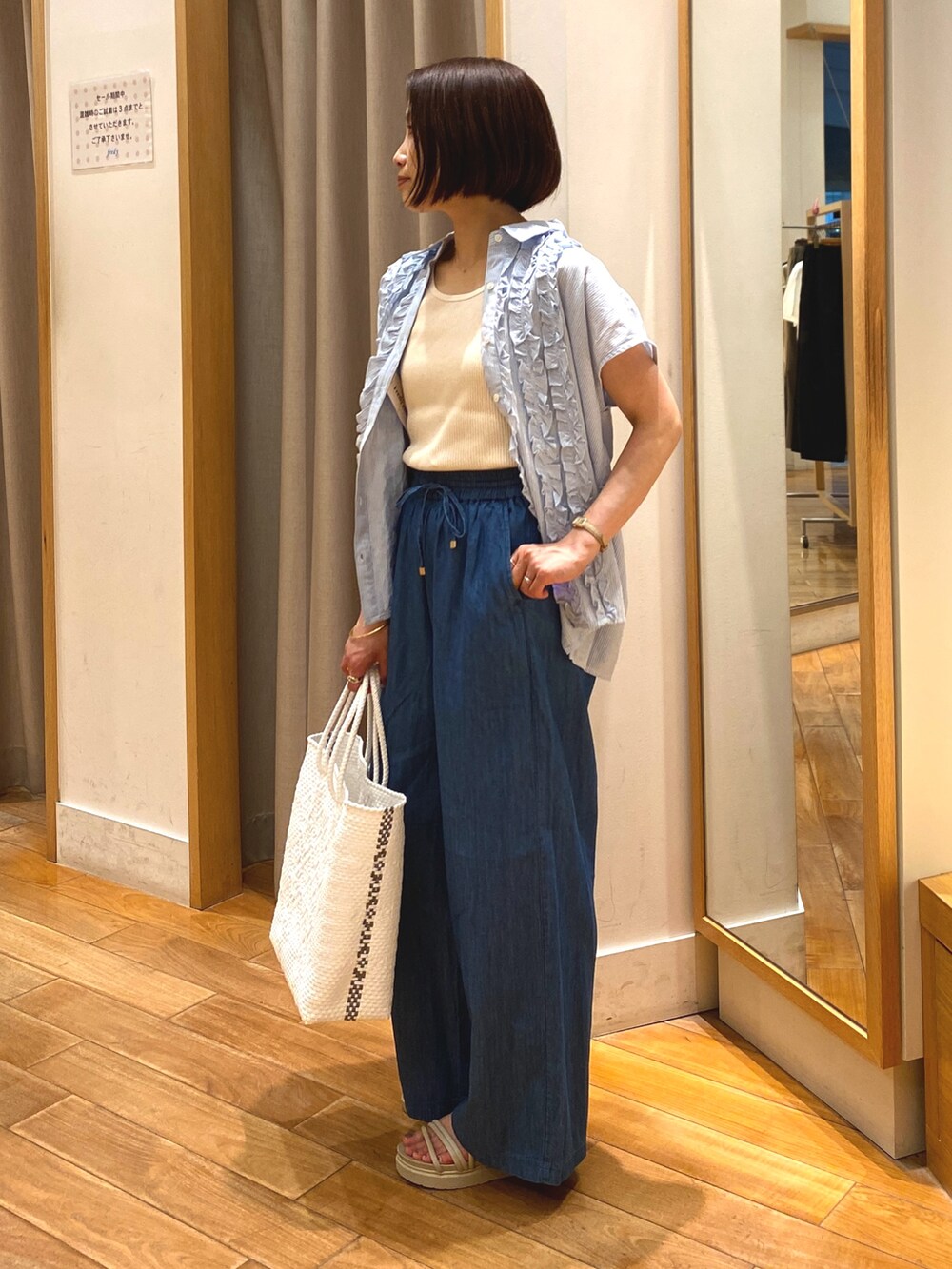 ブルー系のデニムパンツ、ホワイト系のかごバッグ、ブルー系のシャツ/ブラウスを着用したレディースの夏コーディネートの2枚目の写真