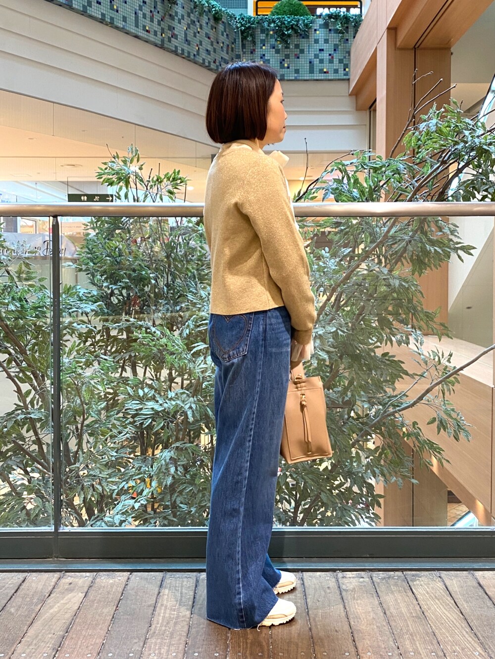 ホワイト系のシャツ/ブラウス、ベージュ系のカーディガン/ボレロ、ブルー系のデニムパンツを着用したレディースの冬コーディネートの4枚目の写真