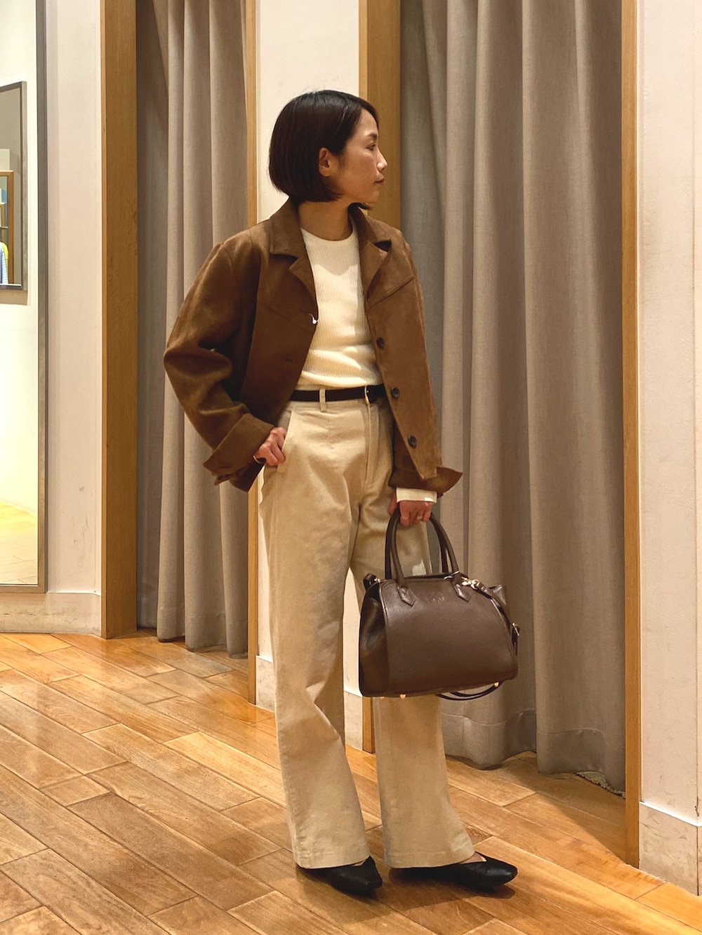 ブラウン系のダウンジャケット/コート、ホワイト系のニット/セーター、ブラウン系のショルダーバッグを着用したレディースの秋コーディネートの2枚目の写真