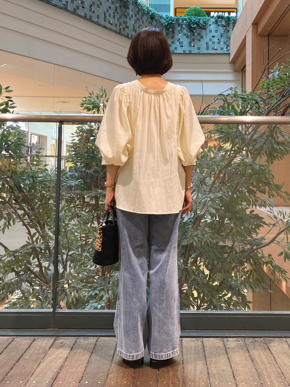 ホワイト系のシャツ/ブラウス、ベージュ系のショルダーバッグ、ブルー系のデニムパンツを着用したレディースの夏コーディネートの4枚目の写真