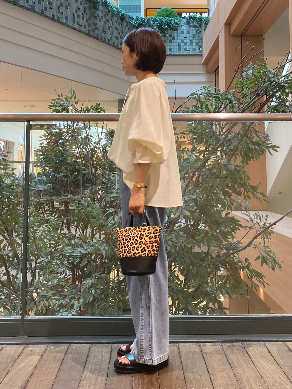 ホワイト系のシャツ/ブラウス、ベージュ系のショルダーバッグ、ブルー系のデニムパンツを着用したレディースの夏コーディネートの2枚目の写真