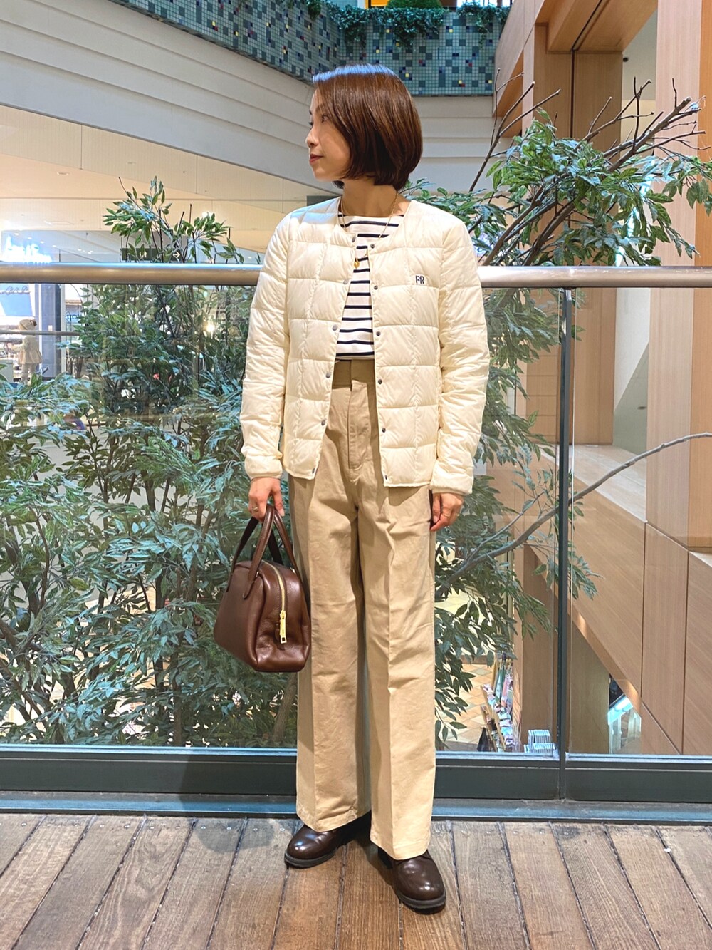 ホワイト系のダウンジャケット/コート、ホワイト系のTシャツ/カットソー、ブラウン系のボストンバッグを着用したレディースの秋コーディネートの2枚目の写真