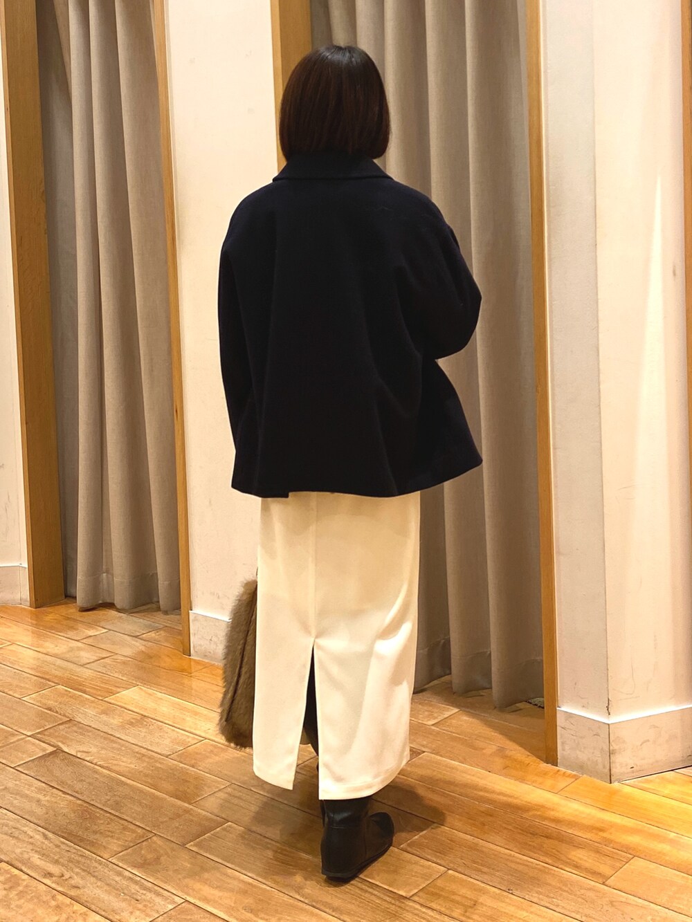 ブルー系のダッフルコート、ブラウン系のニット/セーター、ホワイト系のTシャツ/カットソーを着用したレディースの冬コーディネートの6枚目の写真