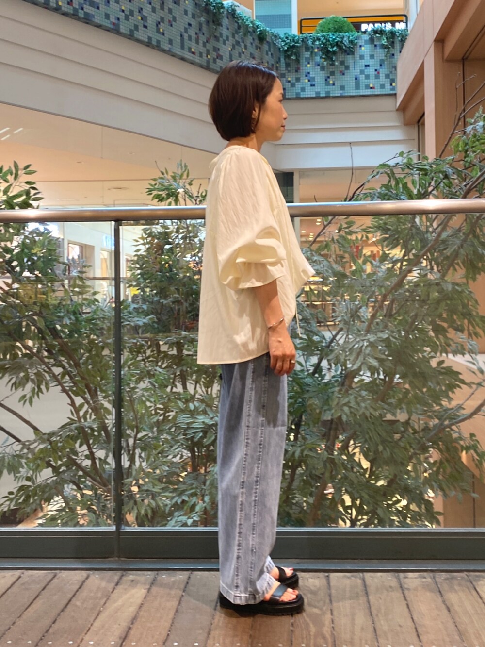 ホワイト系のシャツ/ブラウス、ベージュ系のショルダーバッグ、ブルー系のデニムパンツを着用したレディースの夏コーディネートの3枚目の写真