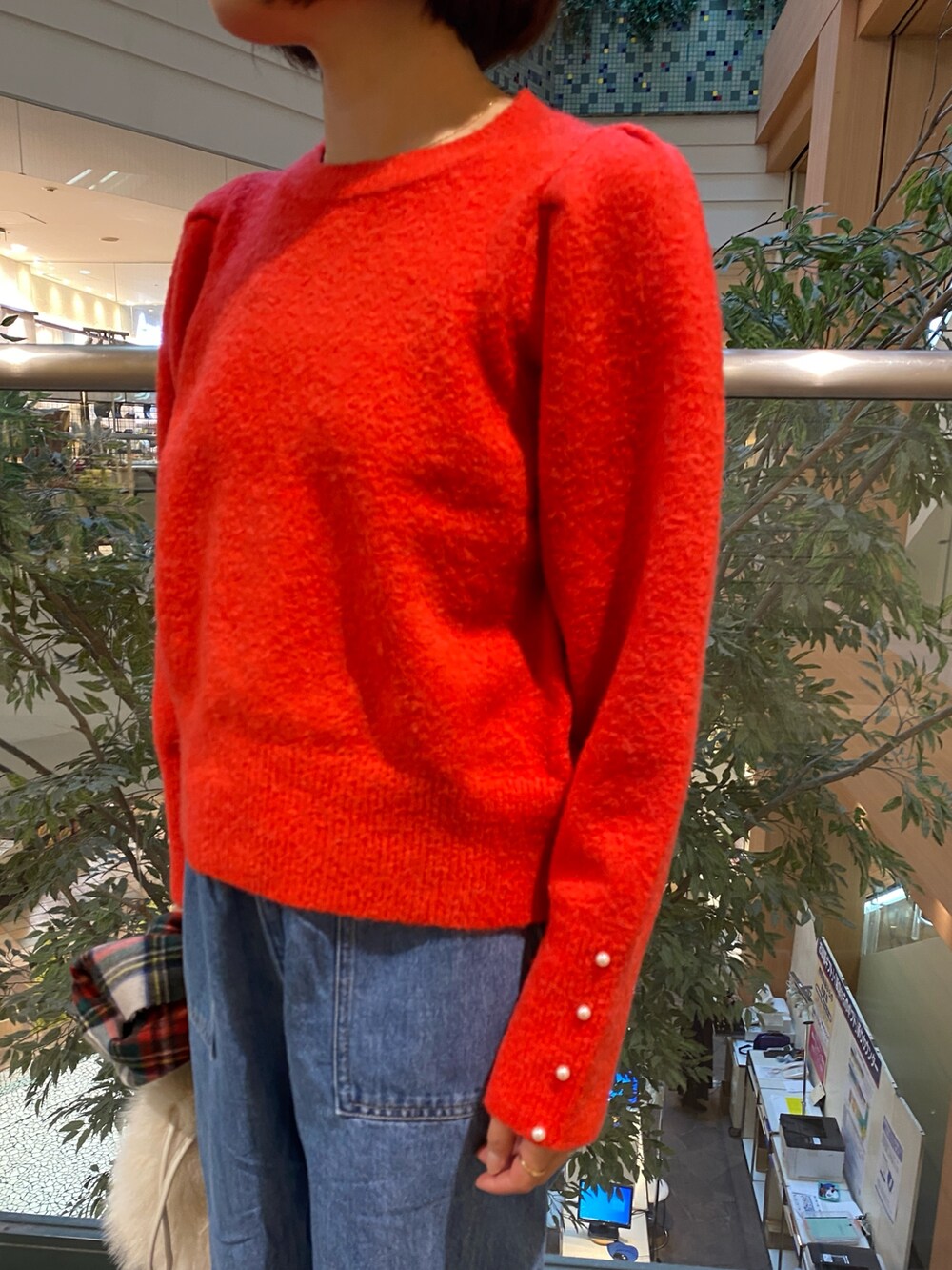 レッド系のニット/セーター、ブルー系のデニムパンツ、ベージュ系のハンドバッグを着用したレディースの冬コーディネートの5枚目の写真