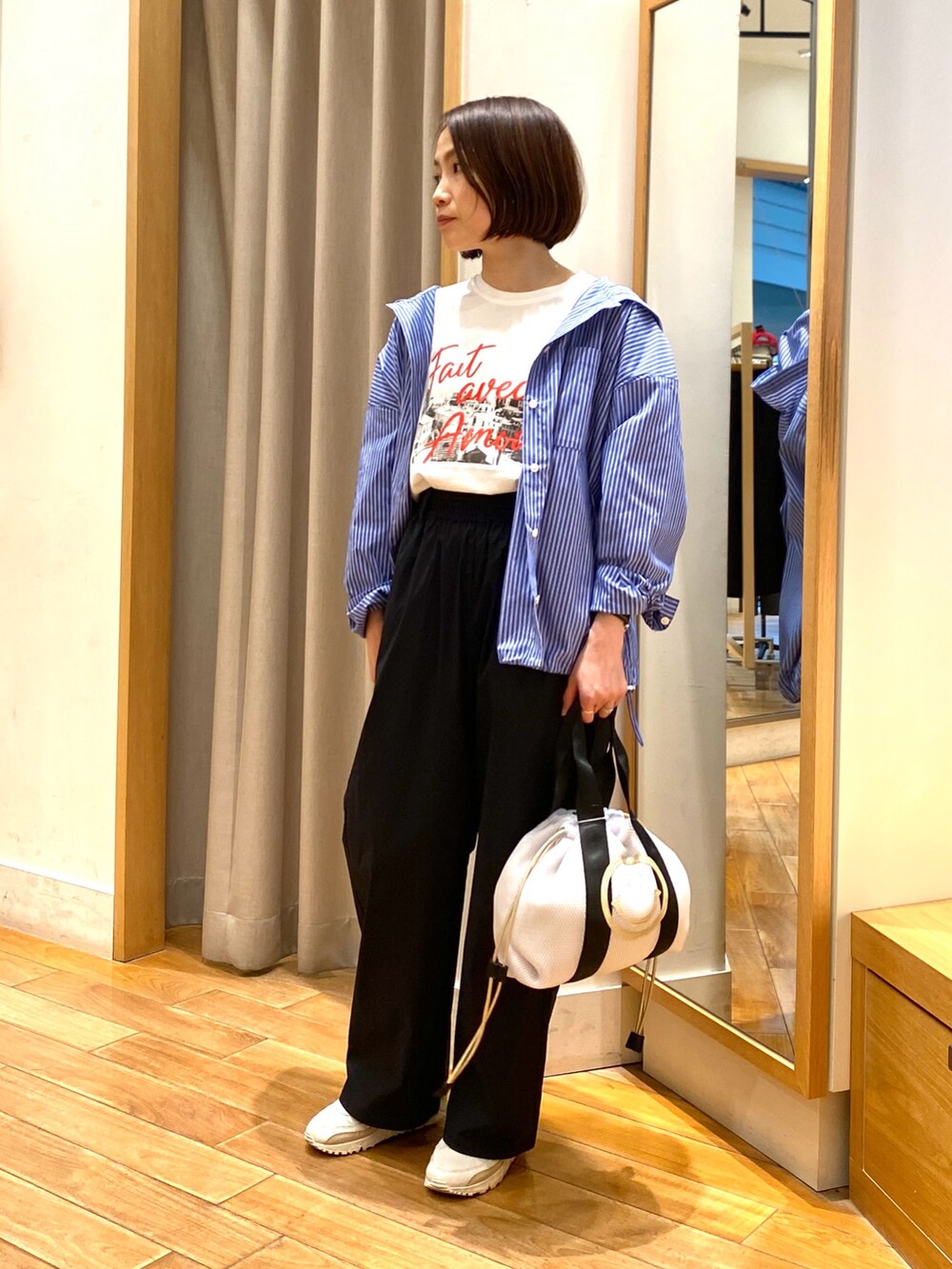 ホワイト系のトートバッグ、ブルー系のシャツ/ブラウス、ホワイト系のTシャツ/カットソーを着用したレディースの春コーディネートの3枚目の写真