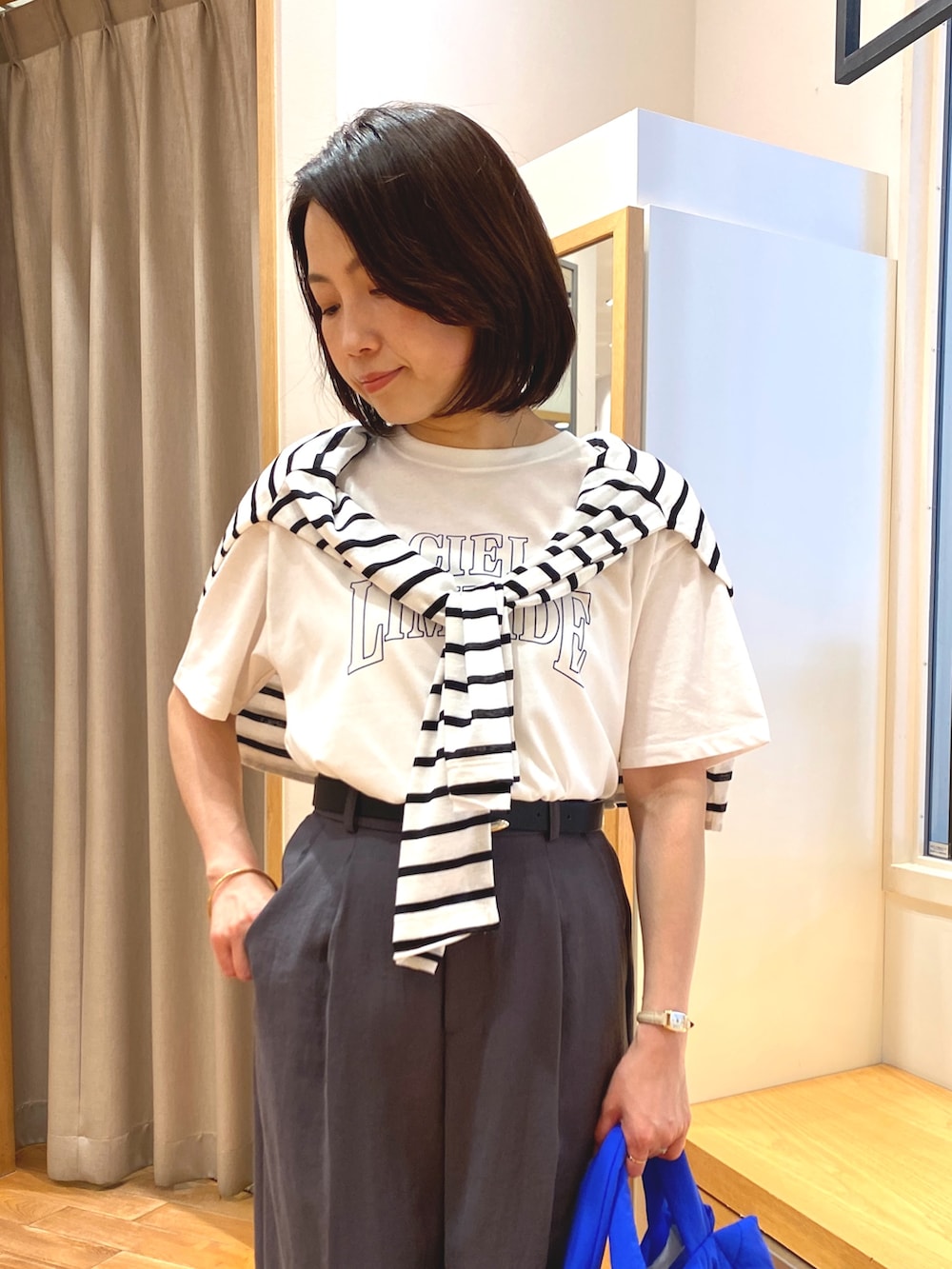 グレー系のスラックス、ブルー系のショルダーバッグ、ホワイト系のTシャツ/カットソーを着用したレディースの夏コーディネートの3枚目の写真