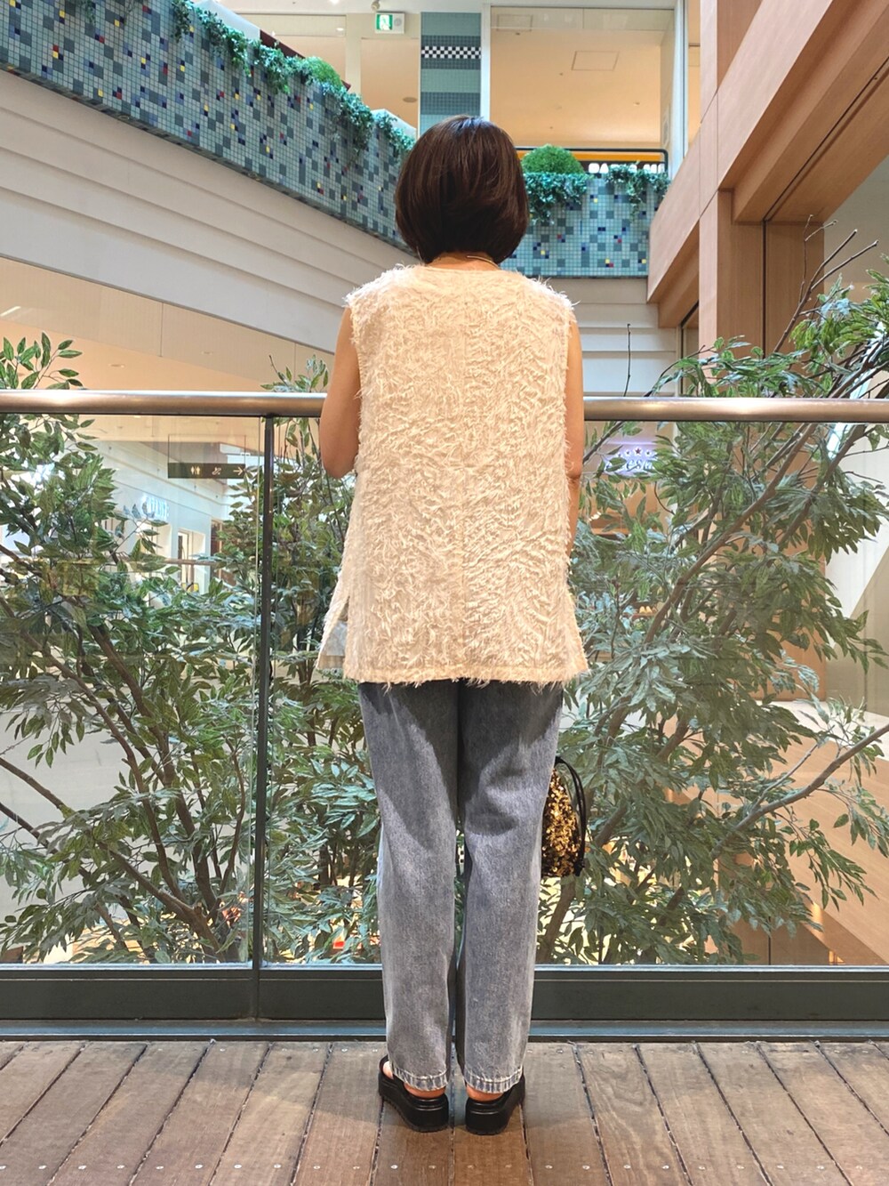 ホワイト系のベスト、ホワイト系のTシャツ/カットソー、ブルー系のデニムパンツを着用したレディースの夏コーディネートの5枚目の写真