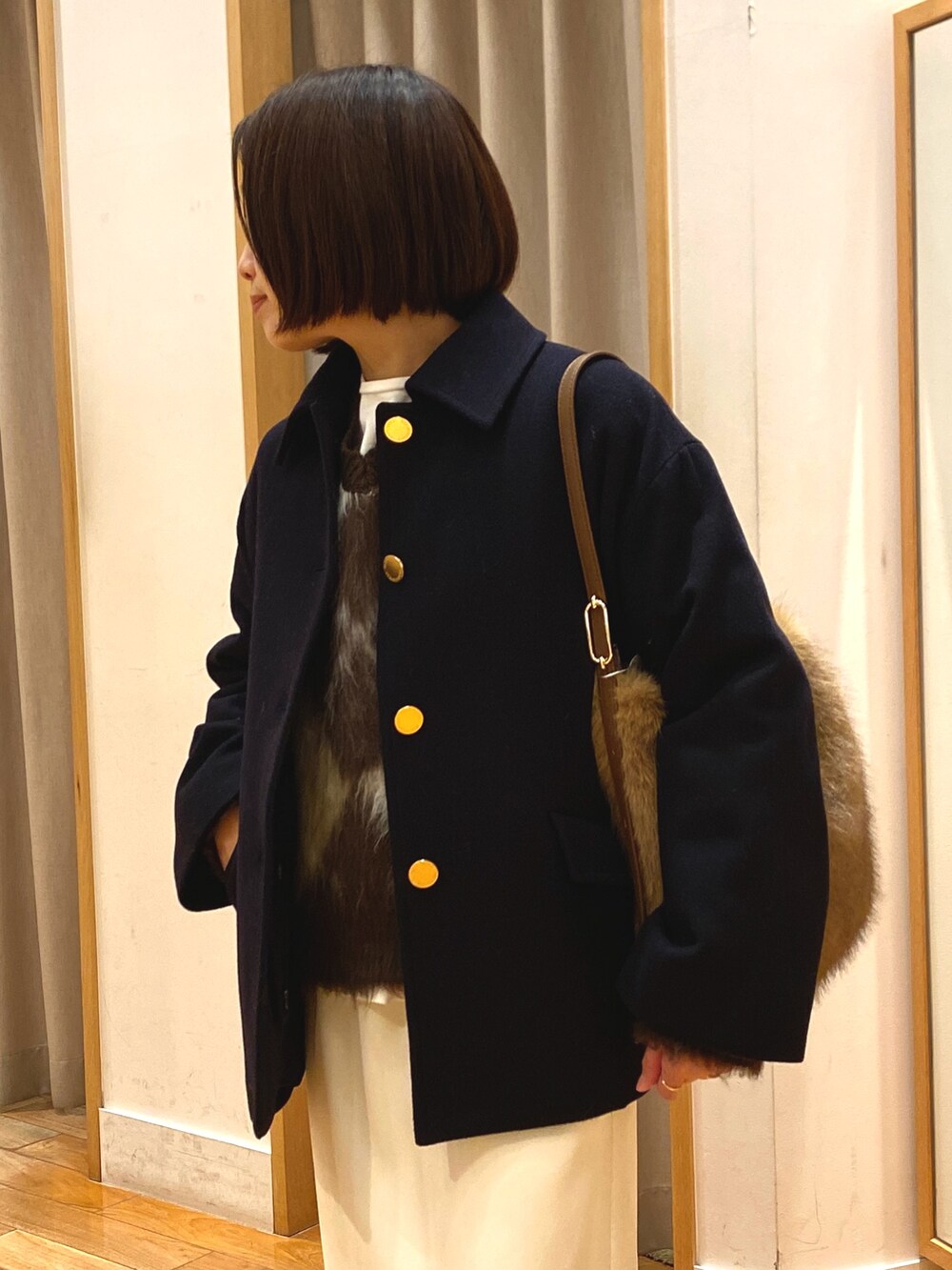 ブルー系のダッフルコート、ブラウン系のニット/セーター、ホワイト系のTシャツ/カットソーを着用したレディースの冬コーディネートの3枚目の写真