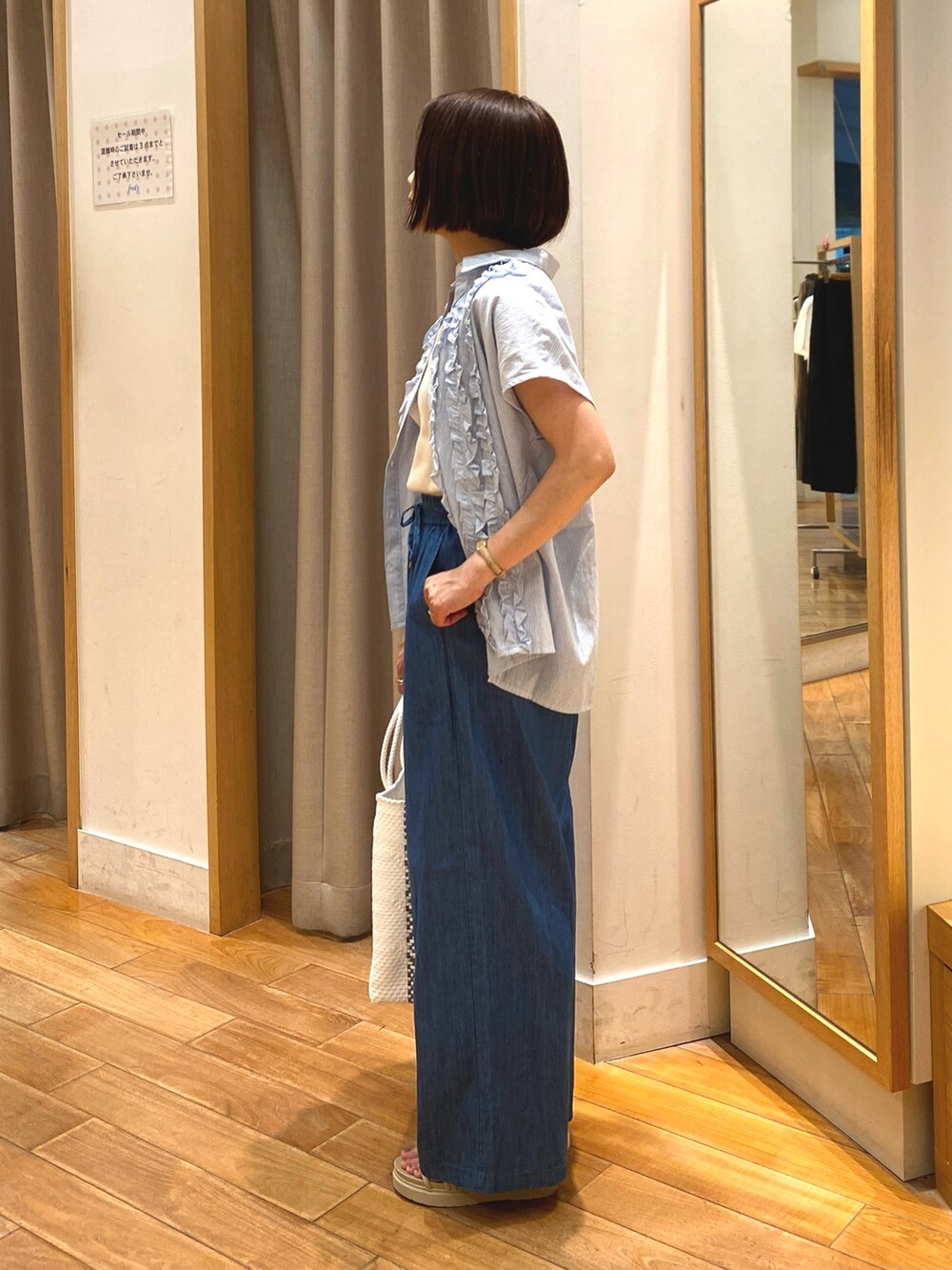 ブルー系のデニムパンツ、ホワイト系のかごバッグ、ブルー系のシャツ/ブラウスを着用したレディースの夏コーディネートの5枚目の写真