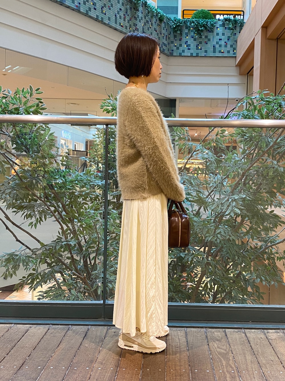 ベージュ系のカーディガン/ボレロ、ホワイト系のTシャツ/カットソー、ホワイト系のスカートを着用したレディースの秋コーディネートの4枚目の写真