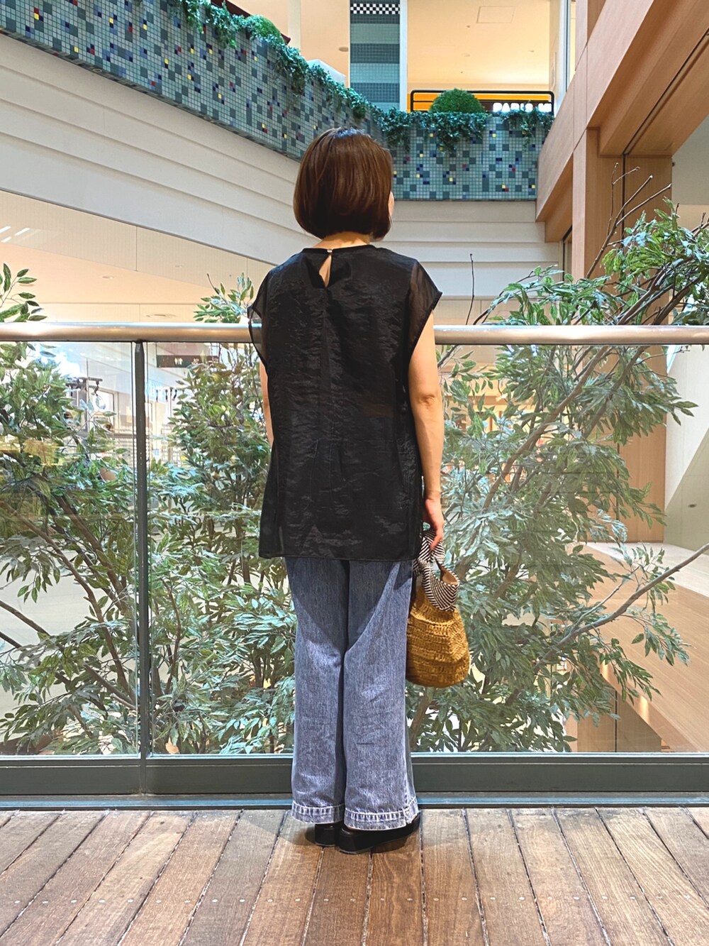 ブラック系のシャツ/ブラウス、ブラウン系のかごバッグ、ブルー系のデニムパンツを着用したレディースの夏コーディネートの5枚目の写真