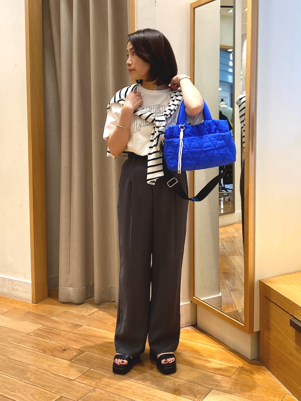 グレー系のスラックス、ブルー系のショルダーバッグ、ホワイト系のTシャツ/カットソーを着用したレディースの夏コーディネートの2枚目の写真