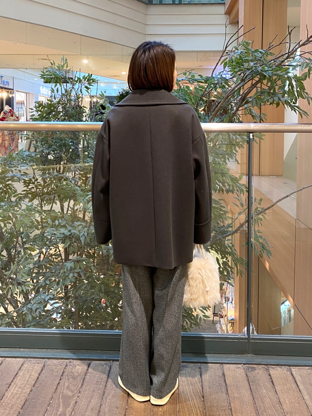 グレー系のピーコート、ホワイト系のその他トップス、グレー系のスラックスを着用したレディースの冬コーディネートの4枚目の写真