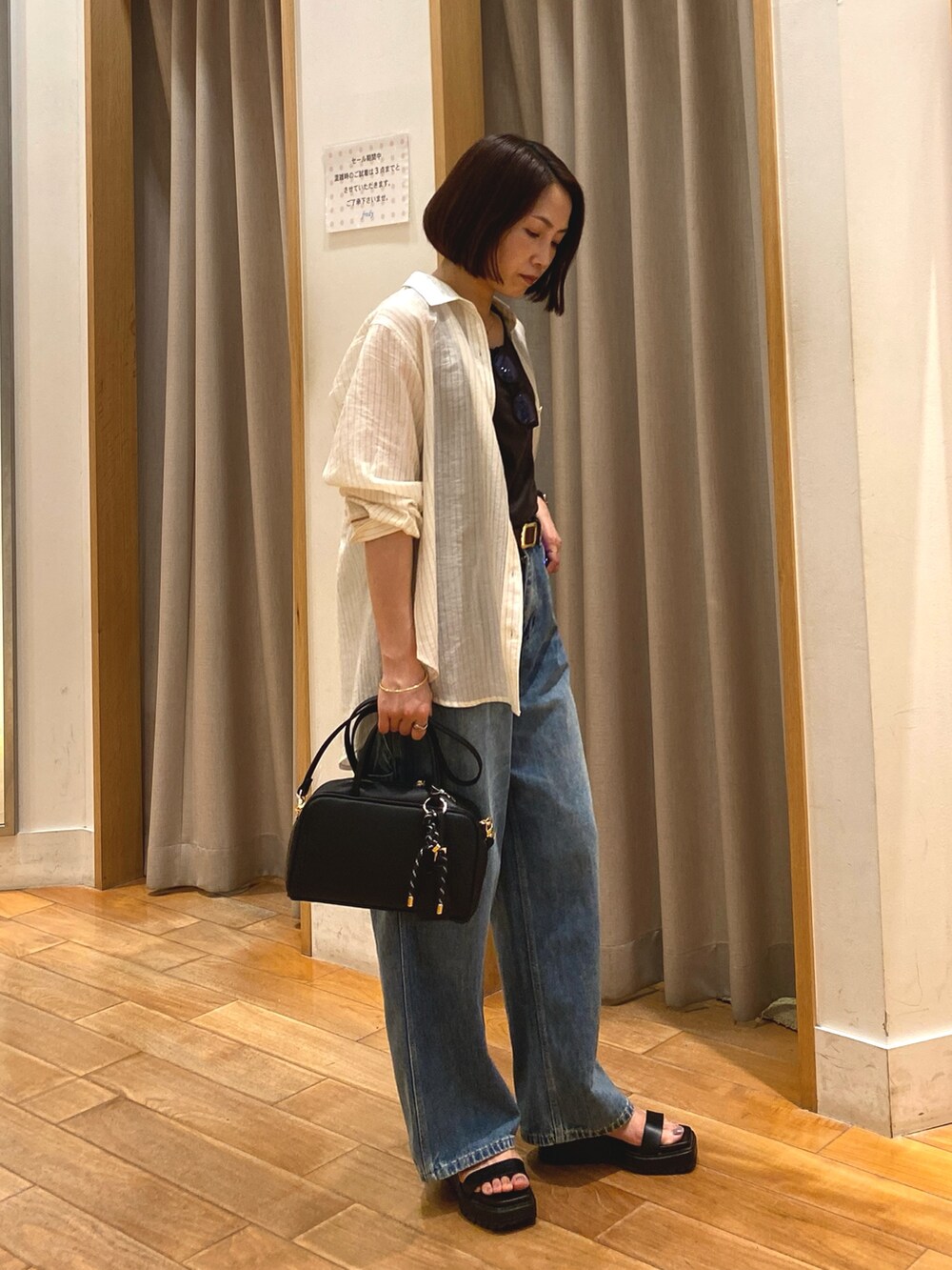 ブルー系のデニムパンツ、ブラック系のショルダーバッグ、ホワイト系のシャツ/ブラウスを着用したレディースの夏コーディネートの5枚目の写真