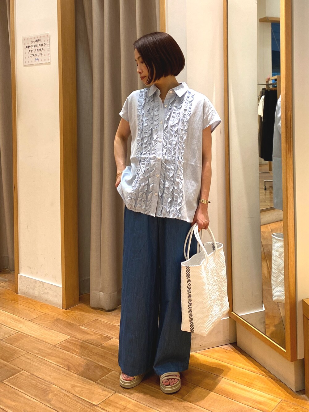 ブルー系のデニムパンツ、ホワイト系のかごバッグ、ブルー系のシャツ/ブラウスを着用したレディースの夏コーディネートの4枚目の写真