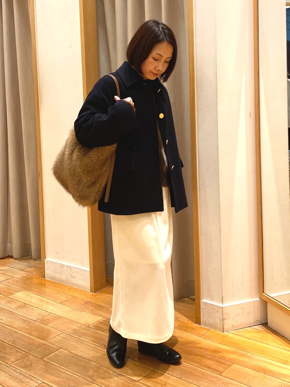 ブルー系のダッフルコート、ブラウン系のニット/セーター、ホワイト系のTシャツ/カットソーを着用したレディースの冬コーディネートの2枚目の写真