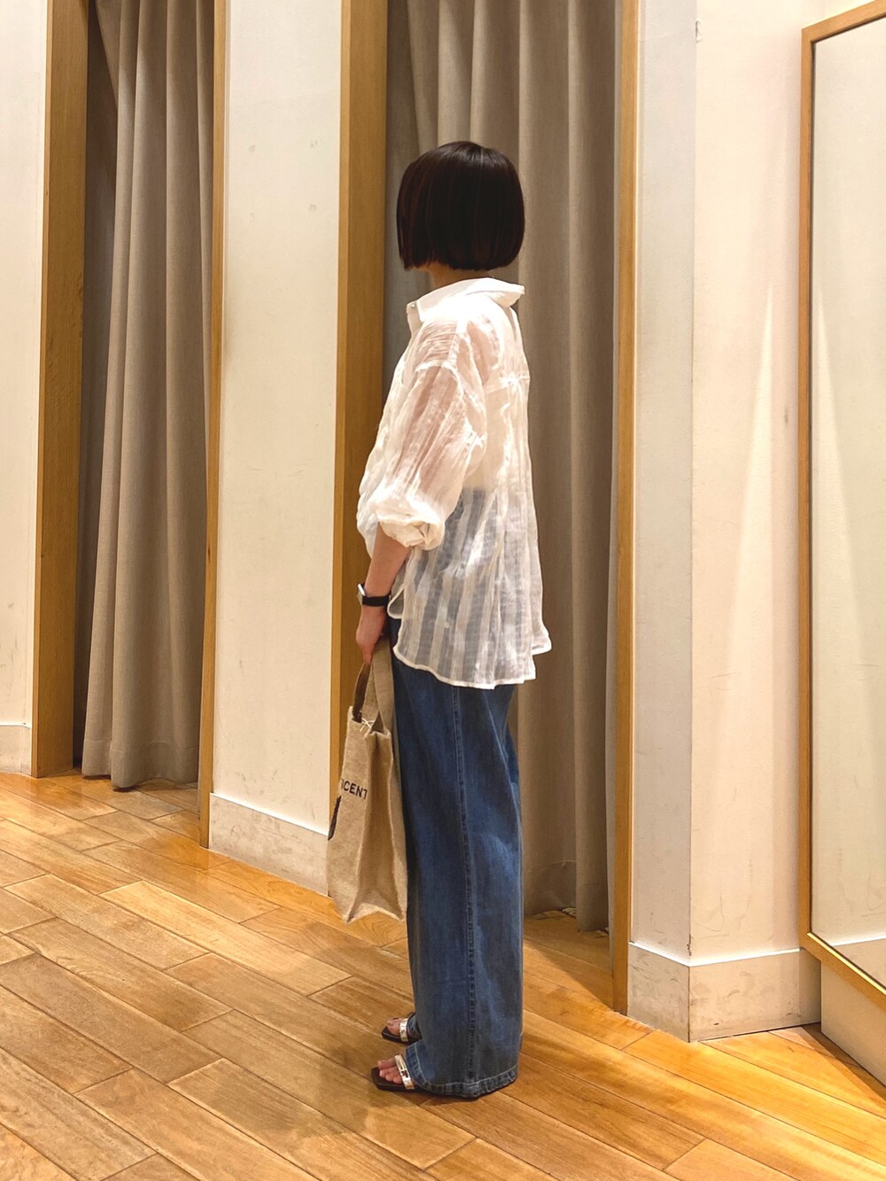 ブルー系のデニムパンツ、ベージュ系のトートバッグ、ホワイト系のシャツ/ブラウスを着用したレディースの春コーディネートの4枚目の写真