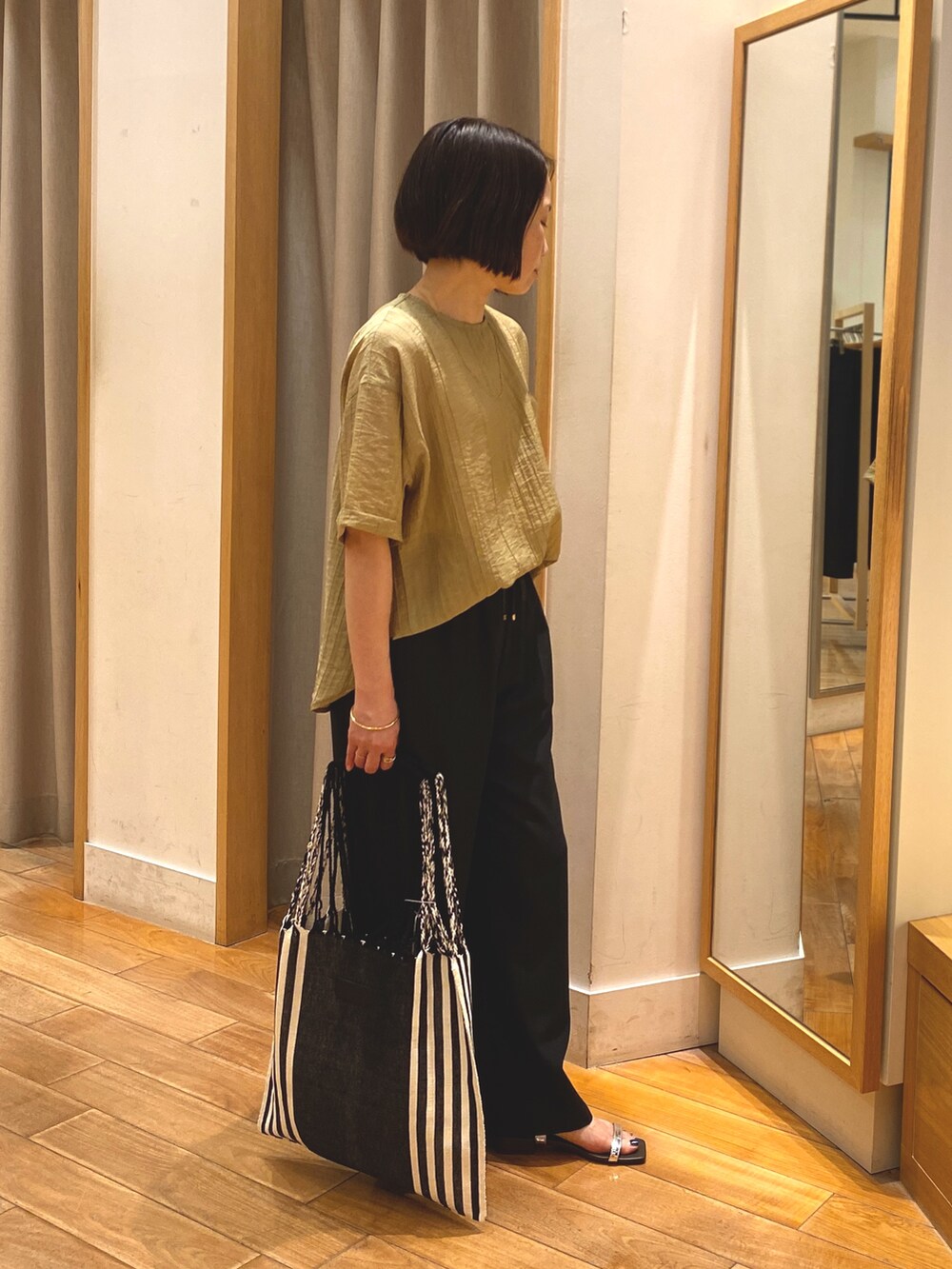 イエロー系のシャツ/ブラウス、グレー系のその他パンツ、ゴールド系のネックレスを着用したレディースの春コーディネートの4枚目の写真