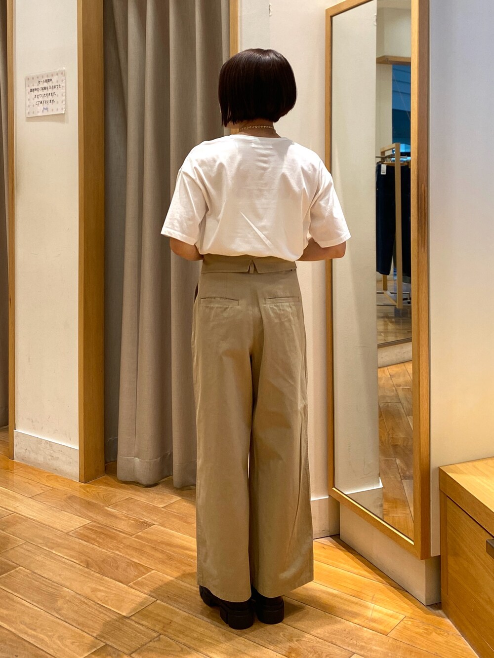 ベージュ系のチノパンツ、ブラック系のショルダーバッグ、ホワイト系のTシャツ/カットソーを着用したレディースの夏コーディネートの3枚目の写真