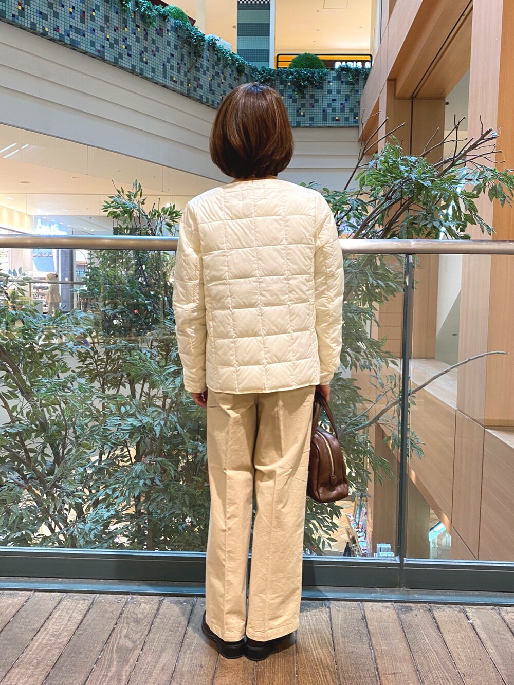 ホワイト系のダウンジャケット/コート、ホワイト系のTシャツ/カットソー、ブラウン系のボストンバッグを着用したレディースの秋コーディネートの5枚目の写真