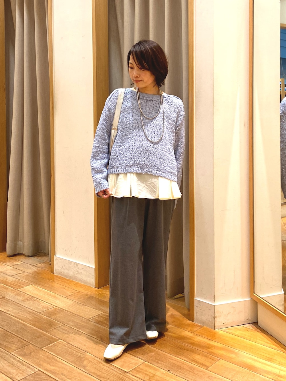 グレー系のその他パンツ、ホワイト系のシャツ/ブラウス、ブルー系のニット/セーターを着用したレディースの春コーディネートの2枚目の写真