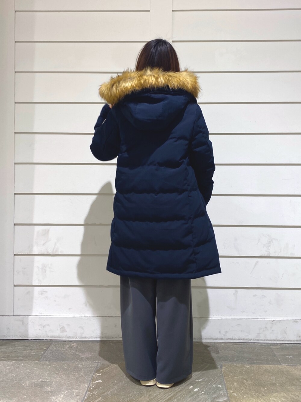 ブルー系のダウンジャケット/コート、ホワイト系のニット/セーター、ブルー系のトートバッグを着用したレディースの冬コーディネートの5枚目の写真