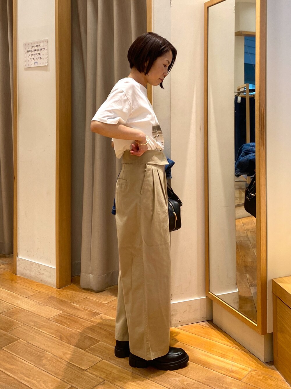 ベージュ系のチノパンツ、ブラック系のショルダーバッグ、ホワイト系のTシャツ/カットソーを着用したレディースの夏コーディネートの2枚目の写真