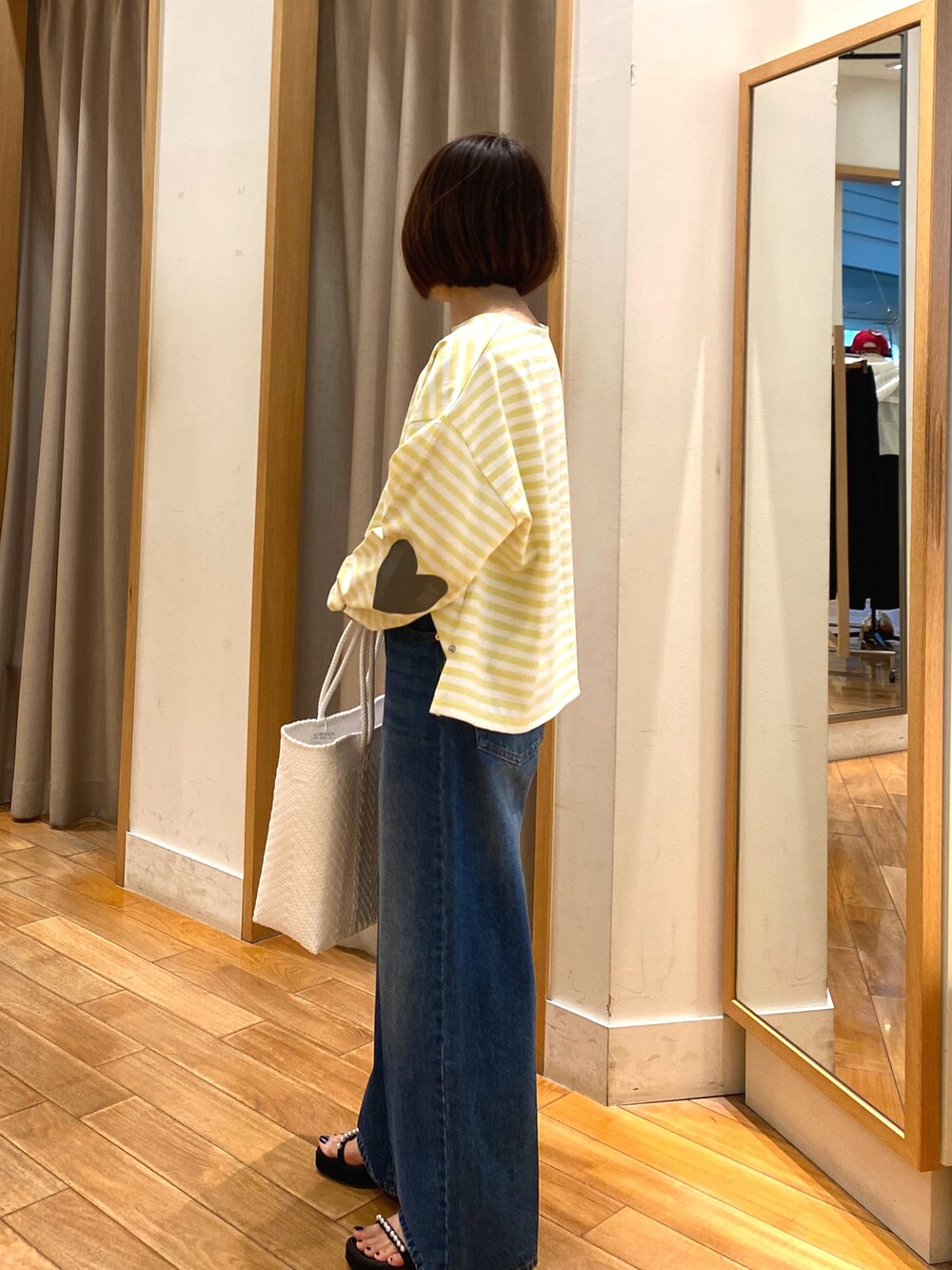 イエロー系のTシャツ/カットソー、ブルー系のデニムパンツ、ホワイト系のかごバッグを着用したレディースの春コーディネートの3枚目の写真