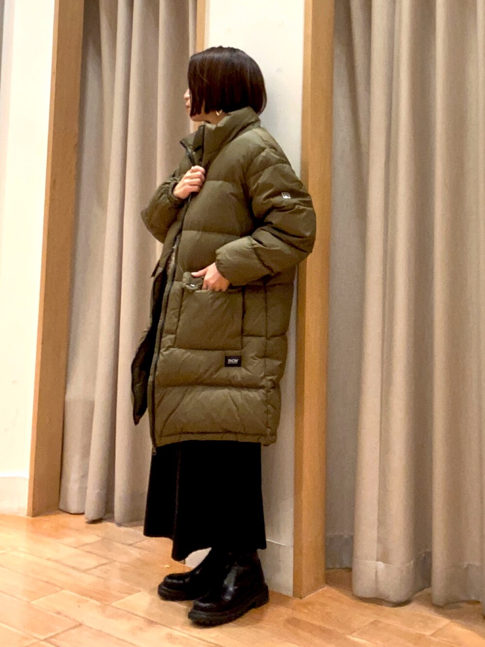 グリーン系のダウンジャケット/コート、ブラック系のスカート、ブラック系のその他トップスを着用したレディースの冬コーディネートの3枚目の写真