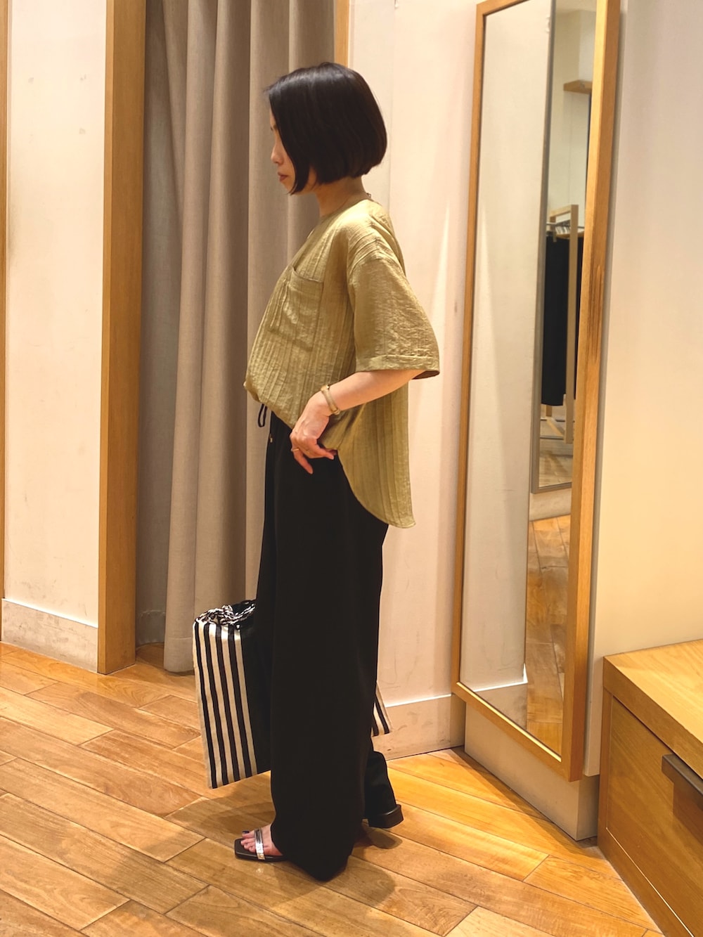 イエロー系のシャツ/ブラウス、グレー系のその他パンツ、ゴールド系のネックレスを着用したレディースの春コーディネートの3枚目の写真