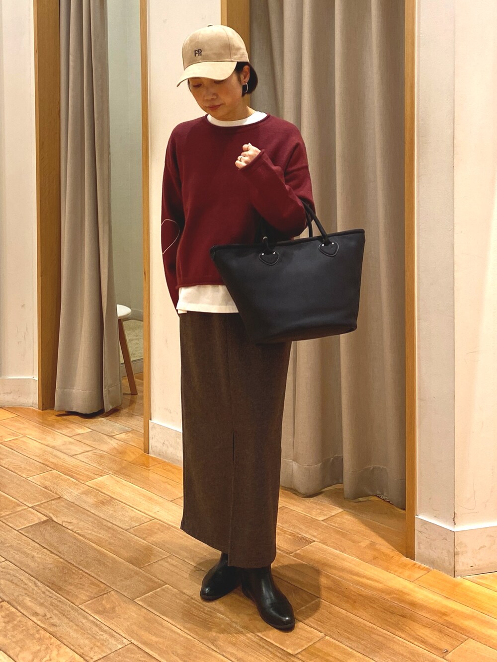 レッド系のニット/セーター、ブラウン系のスカート、ホワイト系のTシャツ/カットソーを着用したレディースの秋コーディネートの3枚目の写真