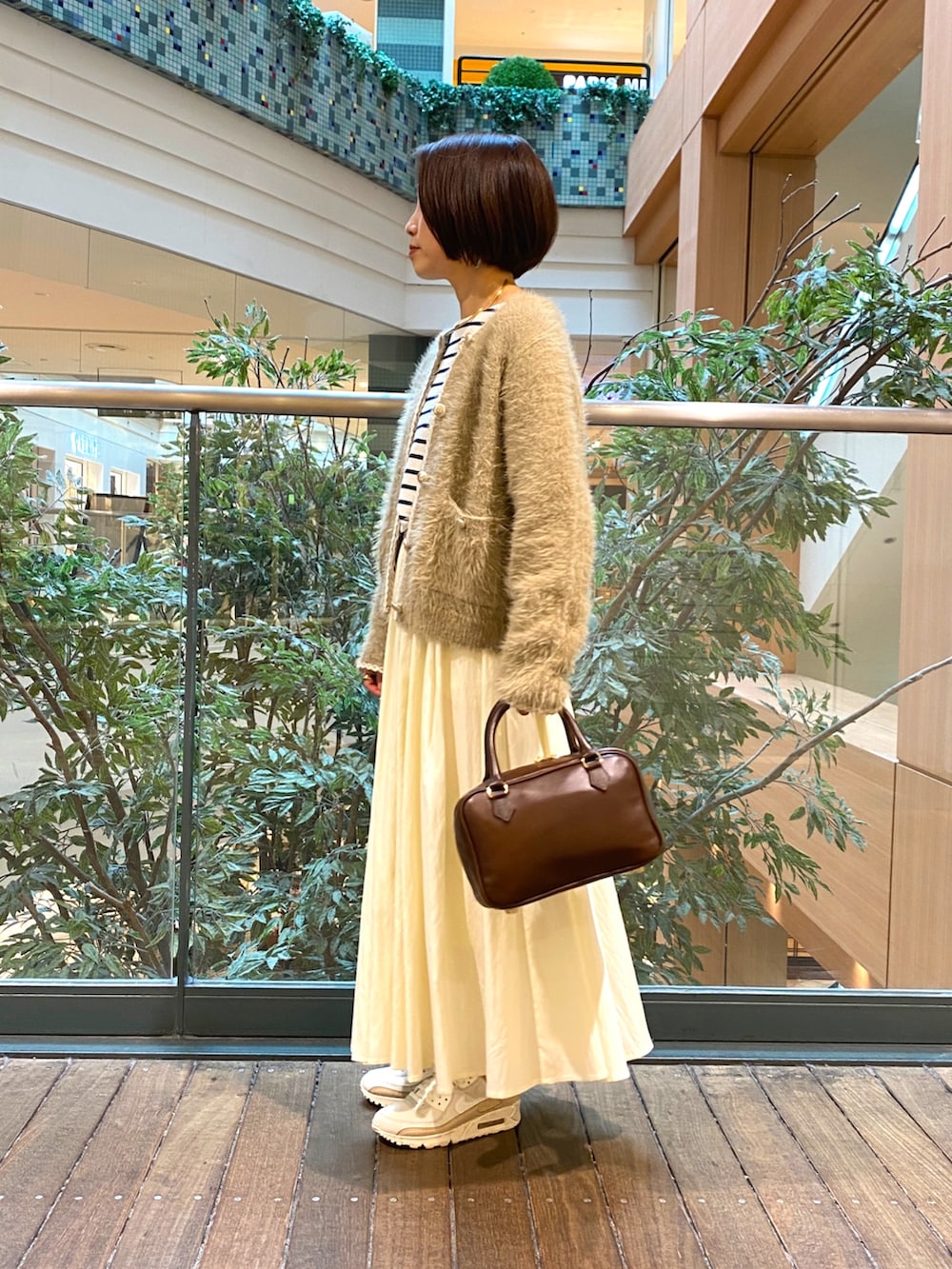 ベージュ系のカーディガン/ボレロ、ホワイト系のTシャツ/カットソー、ホワイト系のスカートを着用したレディースの秋コーディネートの3枚目の写真