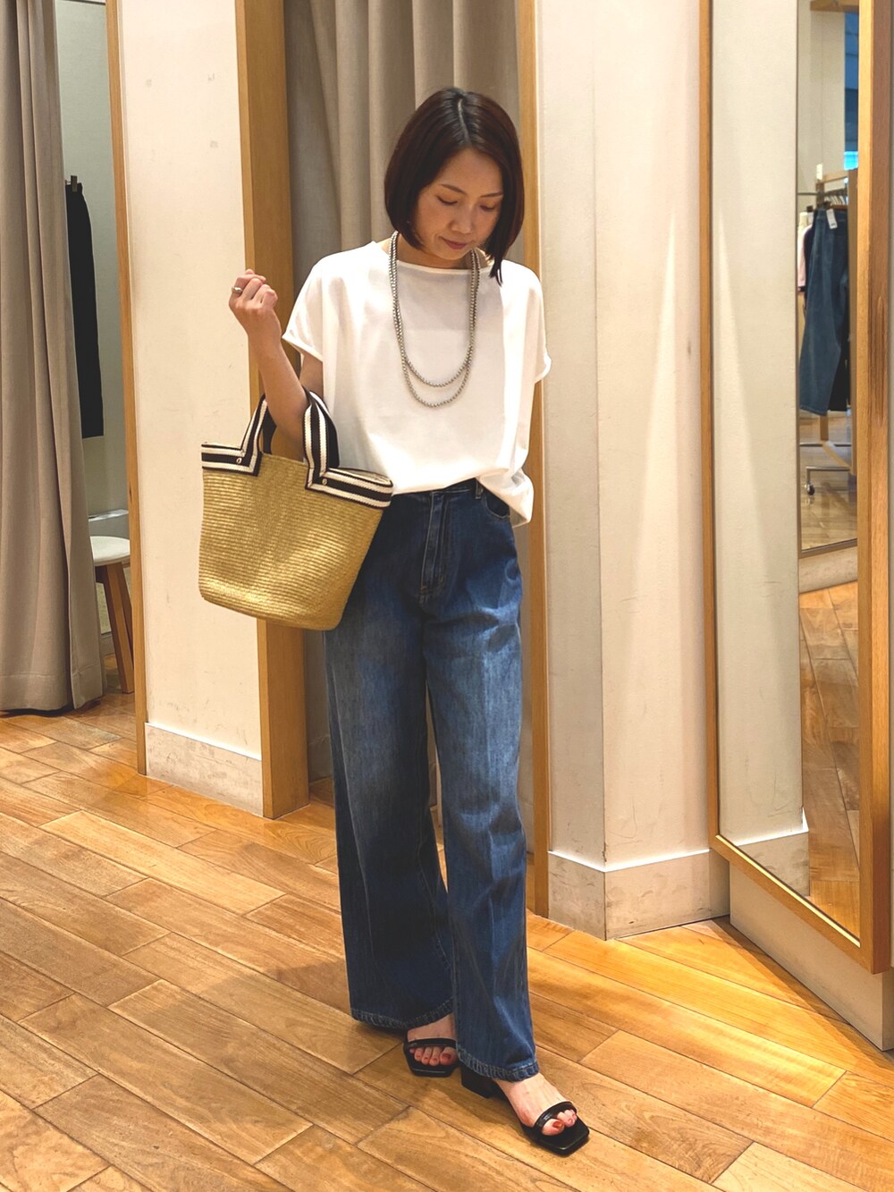ブルー系のデニムパンツ、ホワイト系のTシャツ/カットソー、ベージュ系のかごバッグを着用したレディースの夏コーディネートの3枚目の写真