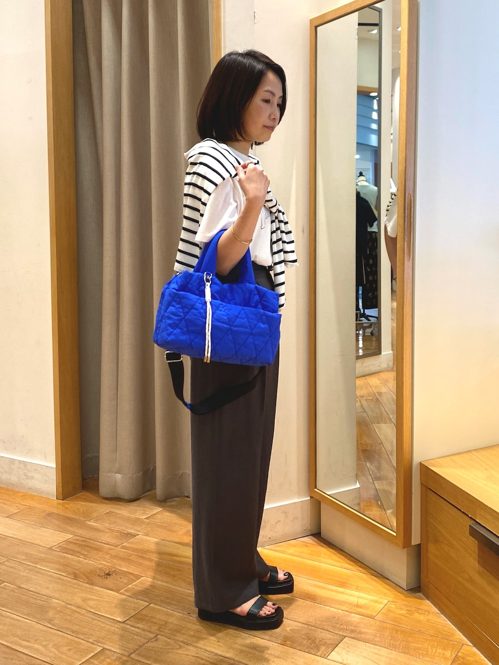 グレー系のスラックス、ブルー系のショルダーバッグ、ホワイト系のTシャツ/カットソーを着用したレディースの夏コーディネートの6枚目の写真