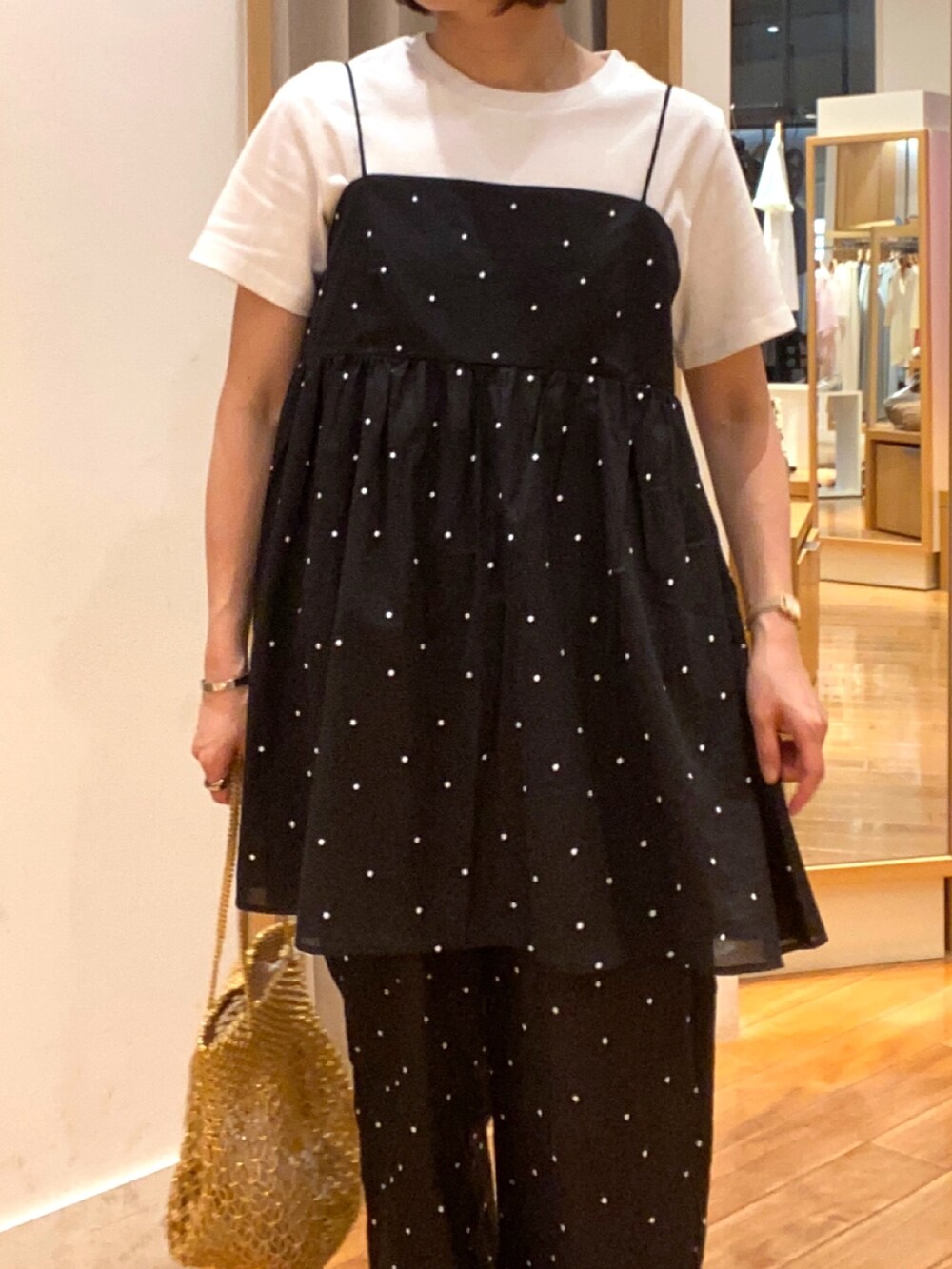 ホワイト系のTシャツ/カットソー、ブラック系のキャミソール、ゴールド系のショルダーバッグを着用したレディースの夏コーディネートの3枚目の写真