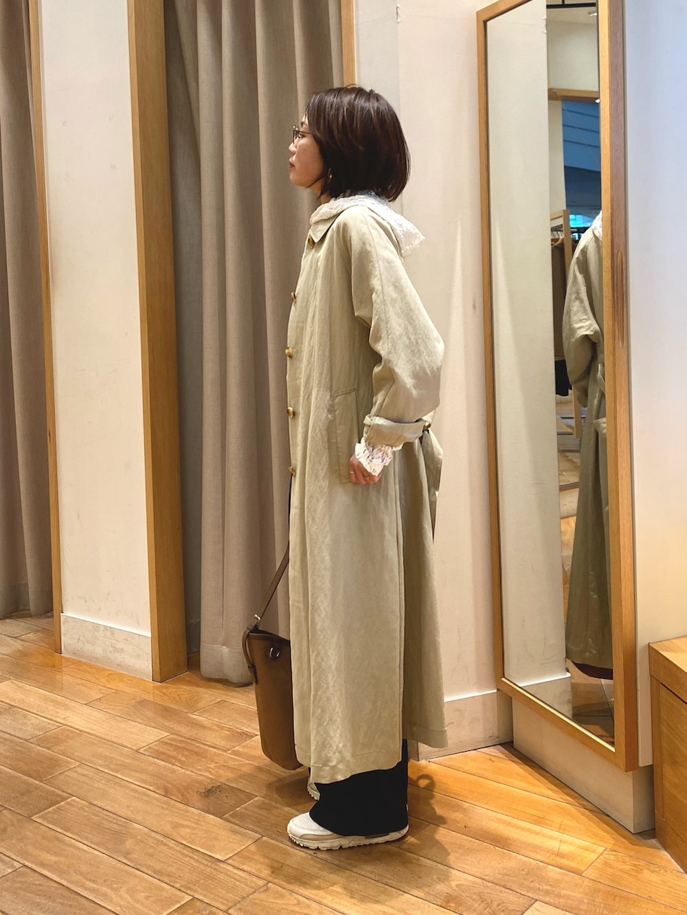 ホワイト系のTシャツ/カットソー、ベージュ系のステンカラーコート、ブラウン系のショルダーバッグを着用したレディースの春コーディネートの5枚目の写真