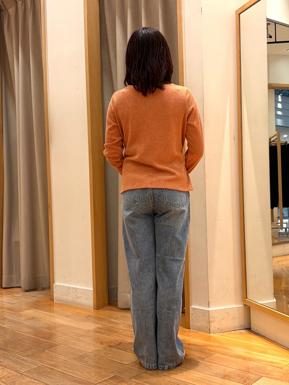 ブルー系のデニムパンツ、ブラウン系のボストンバッグ、オレンジ系のTシャツ/カットソーを着用したレディースの秋コーディネートの8枚目の写真