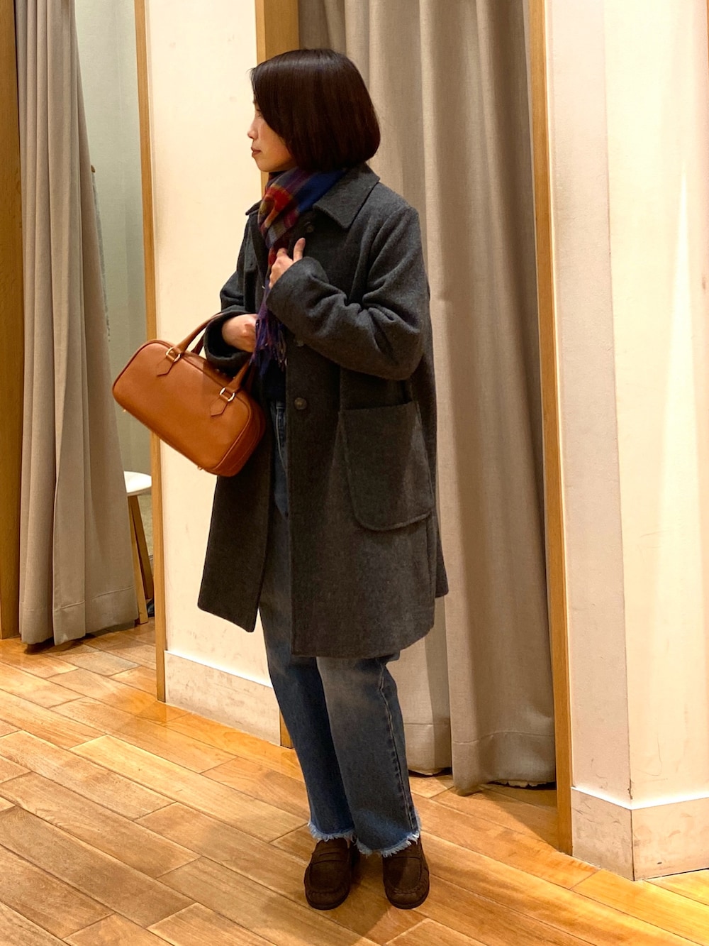 グレー系のダッフルコート、ブルー系のニット/セーター、ブルー系のデニムパンツを着用したレディースの冬コーディネートの2枚目の写真