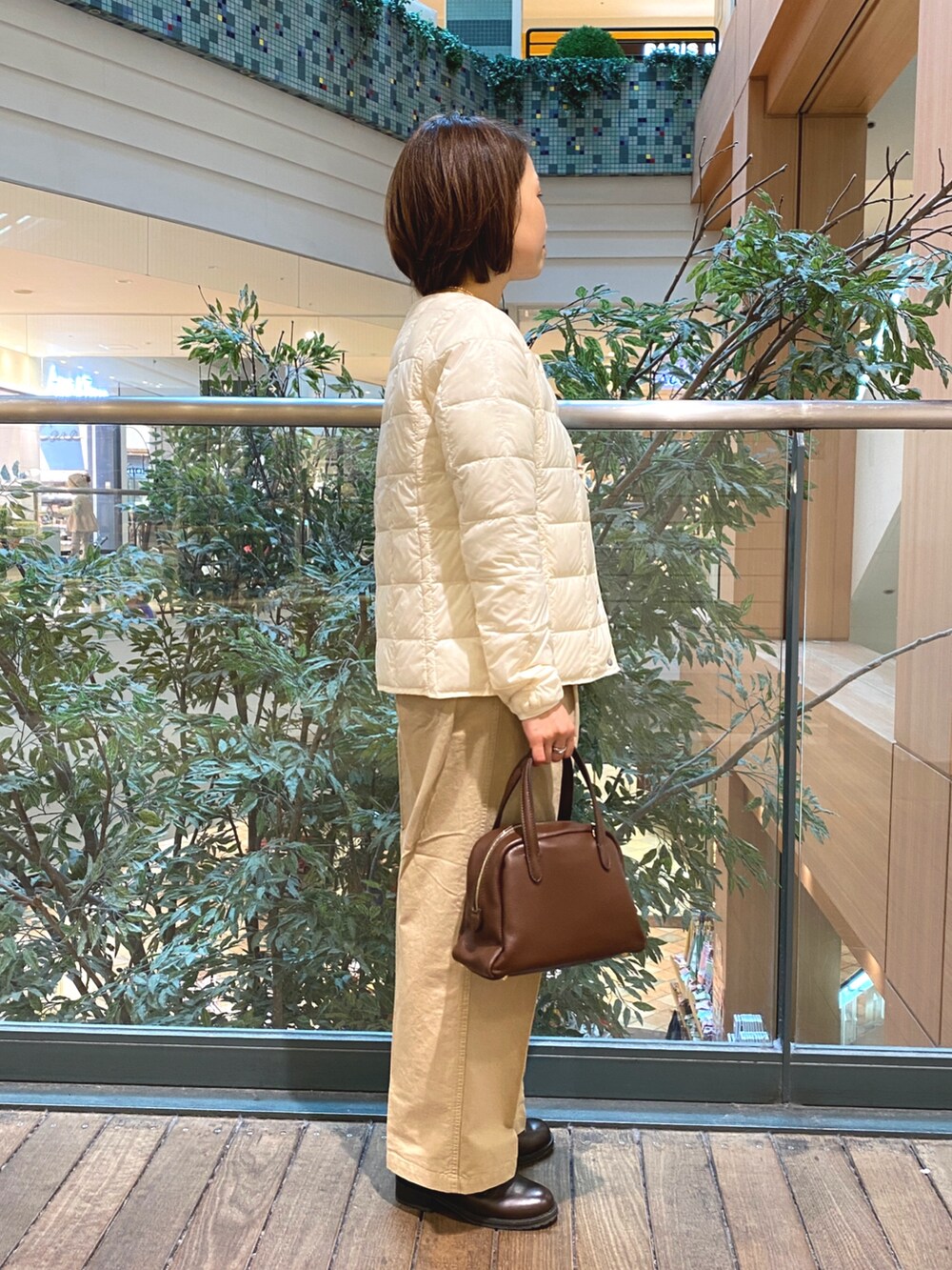 ホワイト系のダウンジャケット/コート、ホワイト系のTシャツ/カットソー、ブラウン系のボストンバッグを着用したレディースの秋コーディネートの4枚目の写真