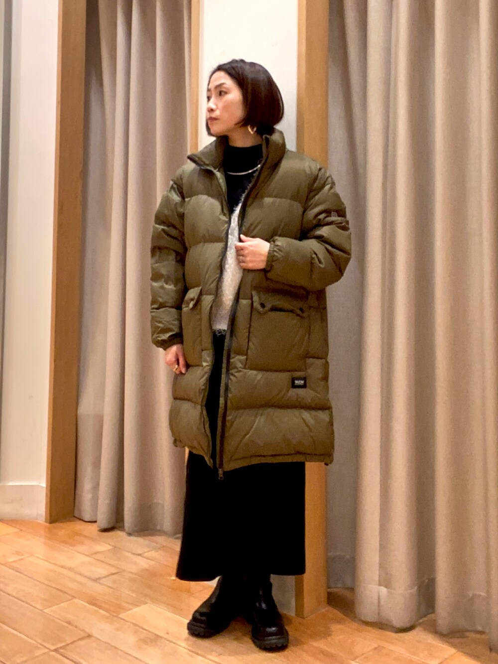 グリーン系のダウンジャケット/コート、ブラック系のスカート、ブラック系のその他トップスを着用したレディースの冬コーディネートの2枚目の写真