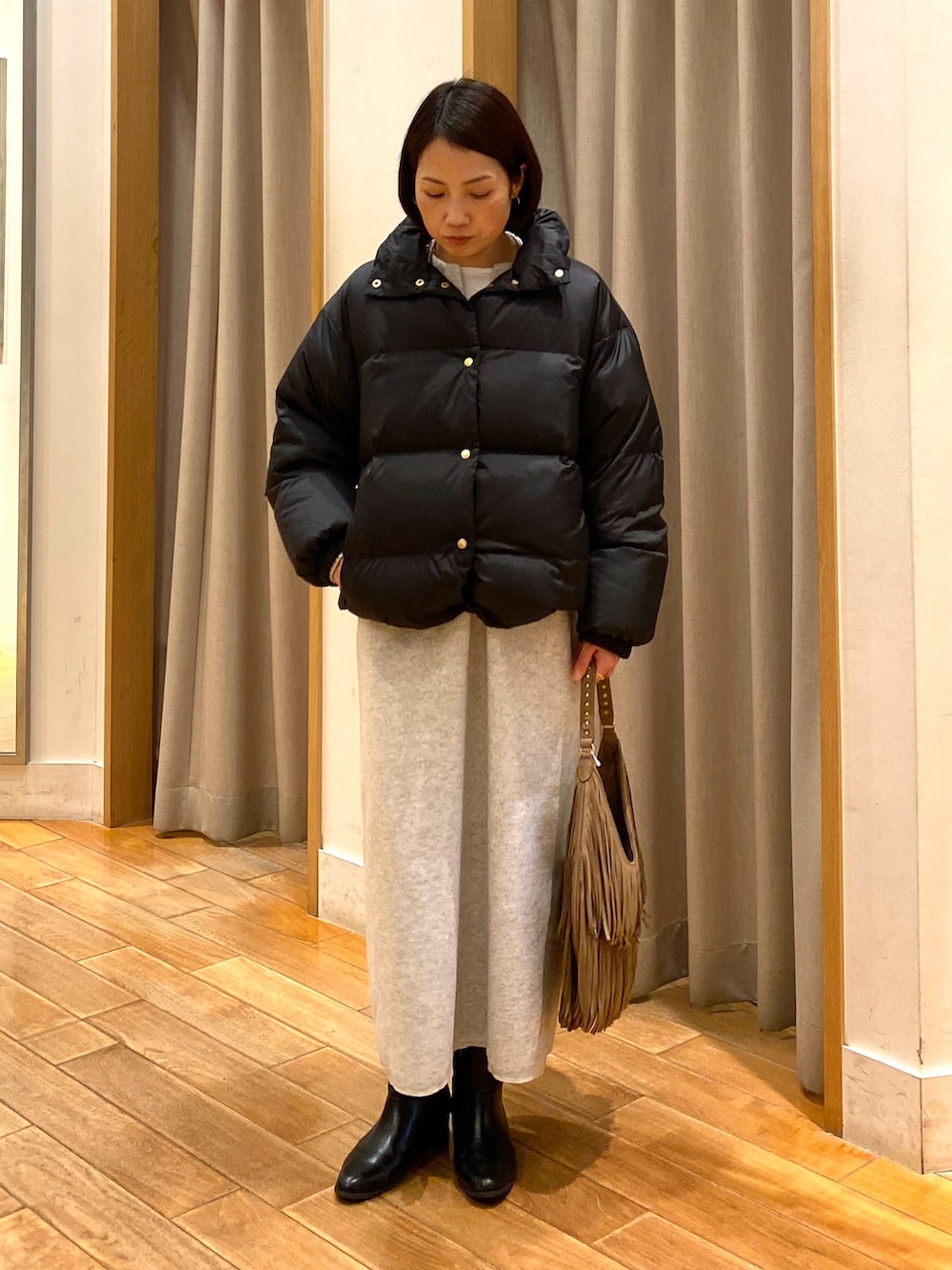 ベージュ系のショルダーバッグ、ブラック系のダウンジャケット/コート、ホワイト系のTシャツ/カットソーを着用したレディースの秋コーディネートの2枚目の写真