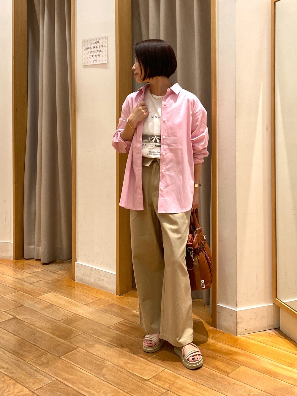 ベージュ系のチノパンツ、ブラック系のショルダーバッグ、ホワイト系のTシャツ/カットソーを着用したレディースの夏コーディネートの5枚目の写真