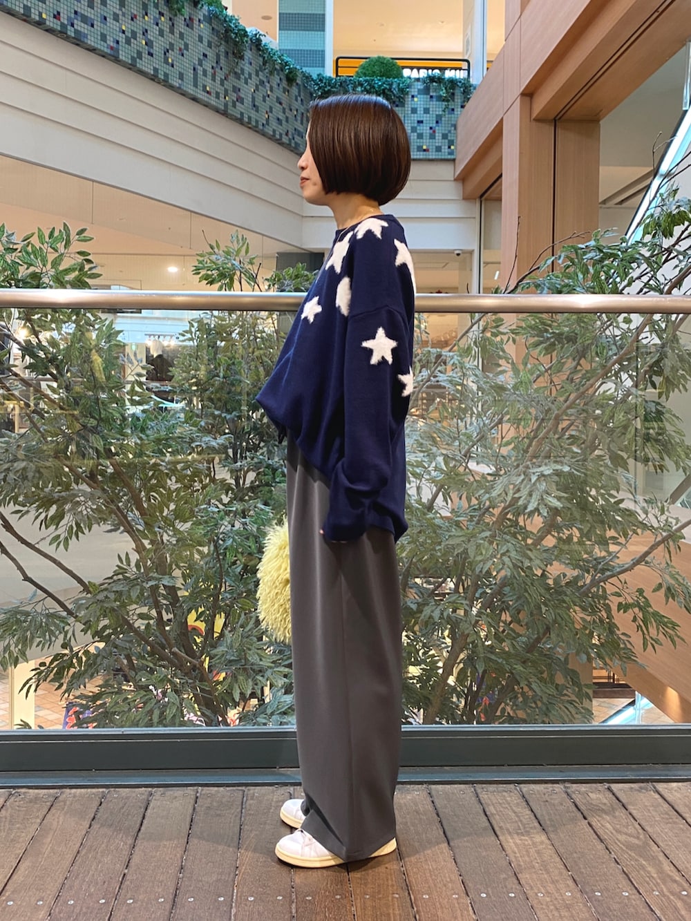 ブルー系のニット/セーター、グレー系のその他パンツ、イエロー系のショルダーバッグを着用したレディースの秋コーディネートの3枚目の写真