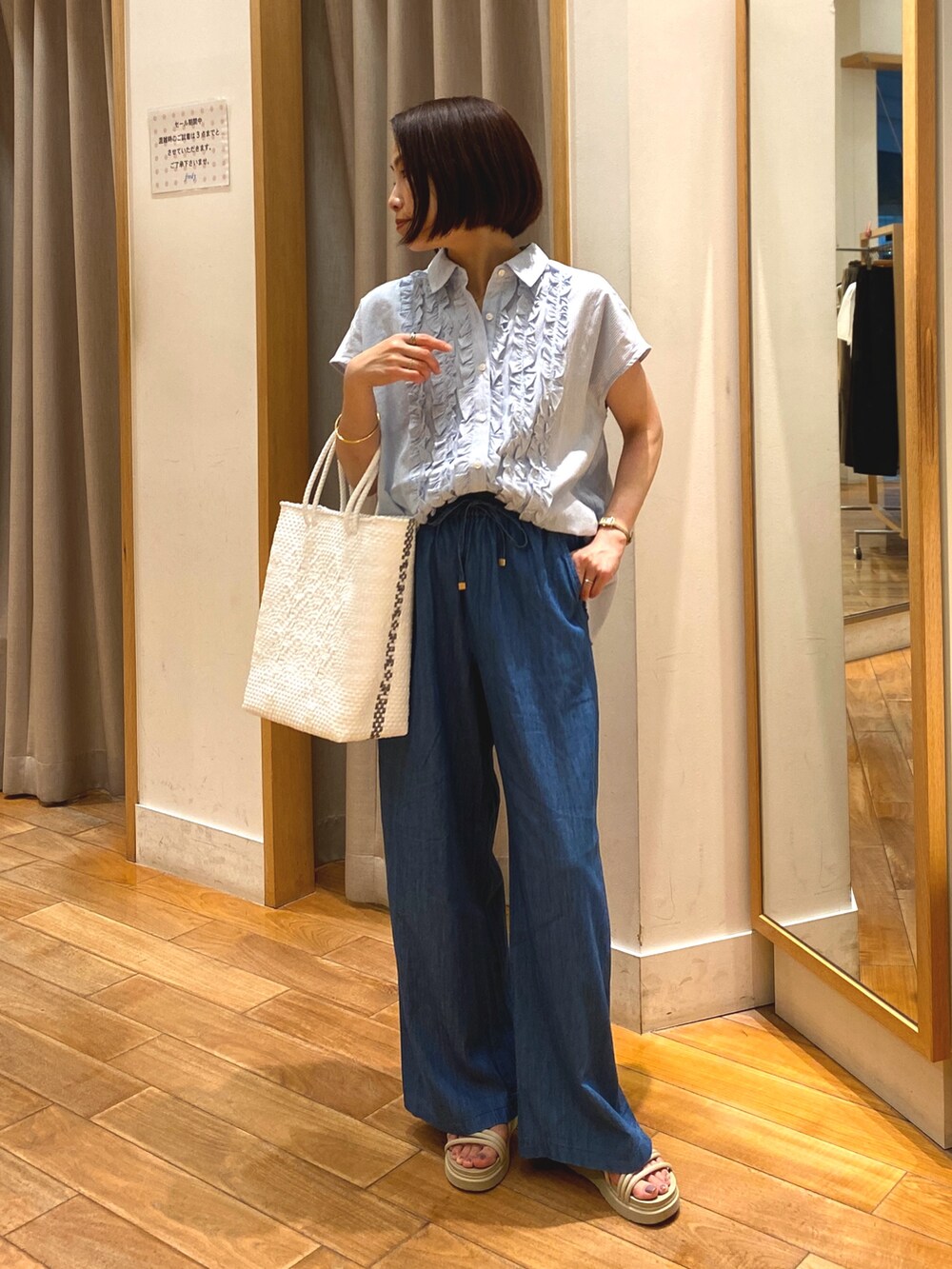 ブルー系のデニムパンツ、ホワイト系のかごバッグ、ブルー系のシャツ/ブラウスを着用したレディースの夏コーディネートの3枚目の写真